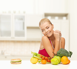 Image showing doubting woman with fruits and hamburger