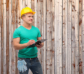 Image showing smiling man in helmet with clipboard