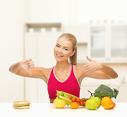 Image showing woman with fruits and hamburger comparing food