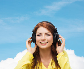 Image showing smiling young girl in headphones at home