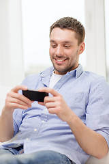 Image showing smiling man with smartphone at home