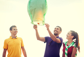 Image showing friends with chinese sky lanterns on the beach