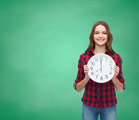 Image showing young woman in casual clothes with wall clock