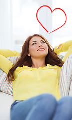 Image showing smiling young woman lying on sofa at home