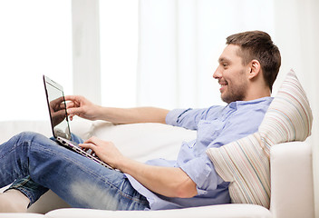 Image showing smiling man working with laptop at home