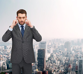 Image showing annoyed businessman covering ears with his hands