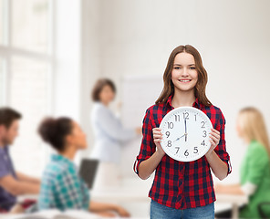 Image showing young woman in casual clothes with wall clock
