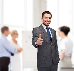 Image showing handsome buisnessman showing thumbs up in office