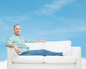 Image showing smiling man lying on sofa