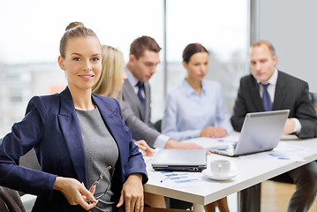 Image showing businesswoman with glasses with team on the back