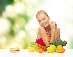 Image showing doubting woman with fruits and hamburger