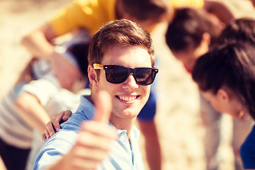 Image showing man with friends on the beach showing thumbs up