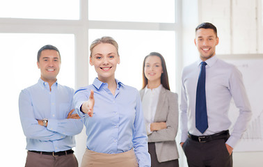 Image showing smiling businesswoman in office with team on back