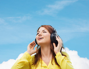 Image showing smiling young girl in headphones at home