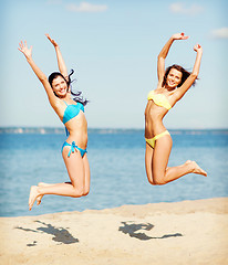 Image showing girls in bikini jumping on the beach