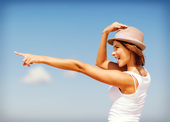 Image showing girl in hat showing direction on the beach