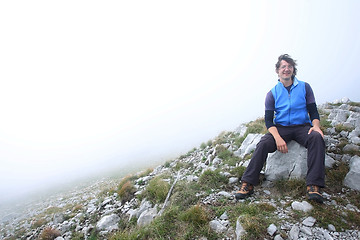 Image showing Man sitting on mountain peak