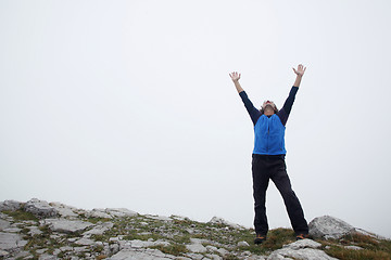 Image showing Man spreading hands on mountain peak