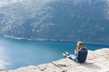 Image showing Woman sitting on Pulpit Rock / Preikestolen, Norway