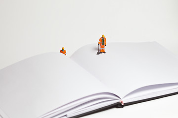 Image showing Miniature people in action worker on an open book