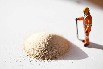 Image showing Miniature worker and a stack of sand