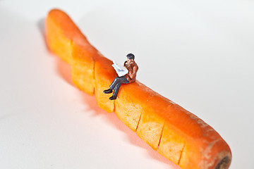 Image showing Miniature people in action sitting on a carrot