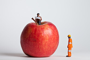 Image showing Miniature people in action sitting on an apple