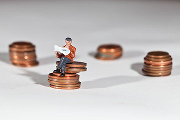 Image showing Miniature people sitting on coins