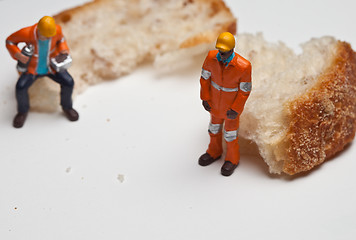 Image showing Miniature people in action with a piece of bread