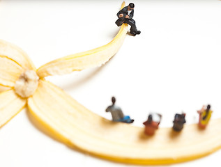 Image showing Miniature people in action stting on a banan