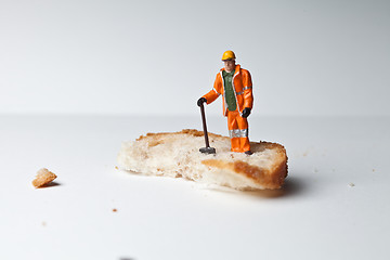 Image showing Miniature people in action with a piece of bread