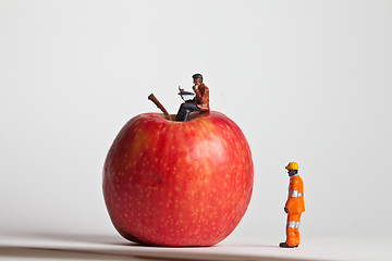 Image showing Miniature people in action sitting on an apple