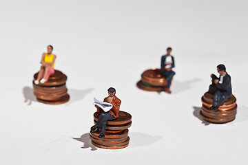 Image showing Miniature people sitting on coins