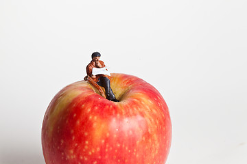 Image showing Miniature people in action sitting on an apple