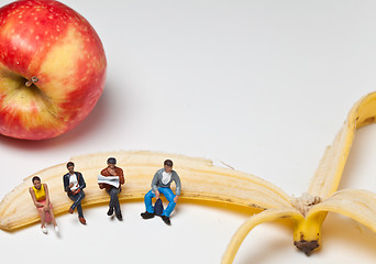Image showing Miniature people in action sitting on a banan