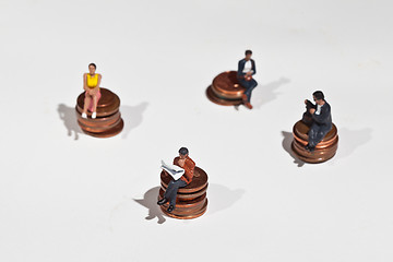 Image showing Miniature people sitting on coins