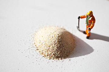 Image showing Miniature worker and a stack of sand