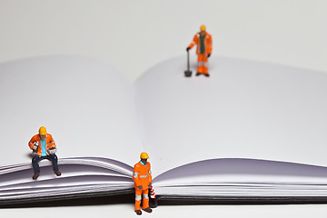 Image showing Miniature people in action worker on an open book