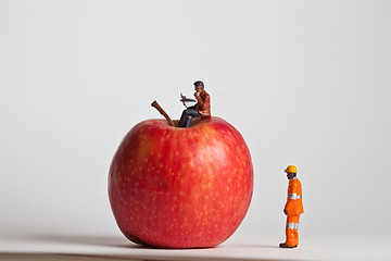 Image showing Miniature people in action sitting on an apple