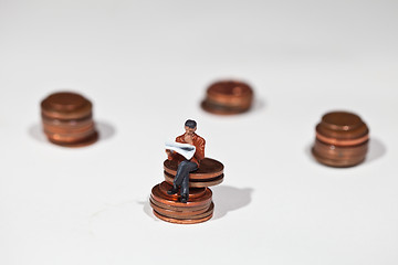 Image showing Miniature people sitting on coins