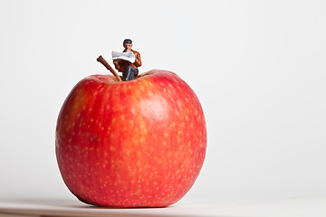 Image showing Miniature people in action sitting on an apple