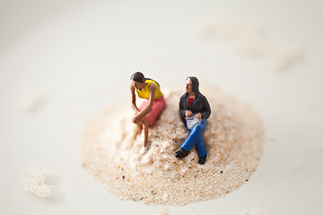 Image showing Miniature people sitting on a stack of sand