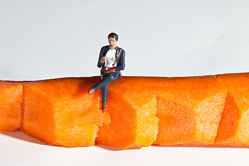 Image showing Miniature people in action sitting on a carrot