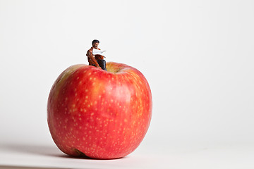 Image showing Miniature people in action sitting on an apple