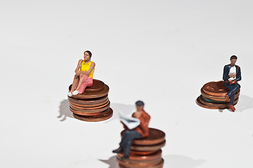 Image showing Miniature people sitting on coins