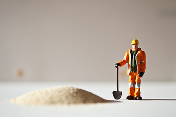 Image showing Miniature worker and a stack of sand