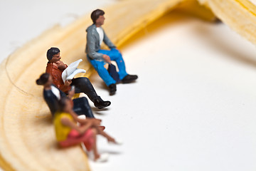 Image showing Miniature people in action stting on a banan