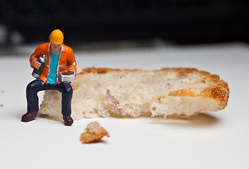 Image showing Miniature people in action with a piece of bread