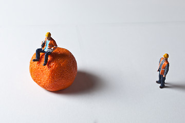 Image showing Miniature people in action and man sitting on an orange