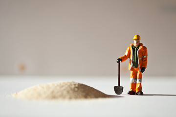 Image showing Miniature worker and a stack of sand